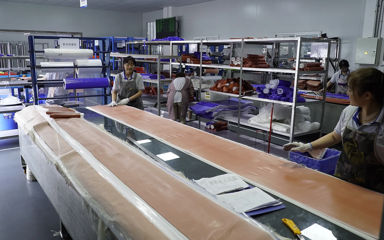 Workers preparing and cutting reinforced silicone sheet in a production work area